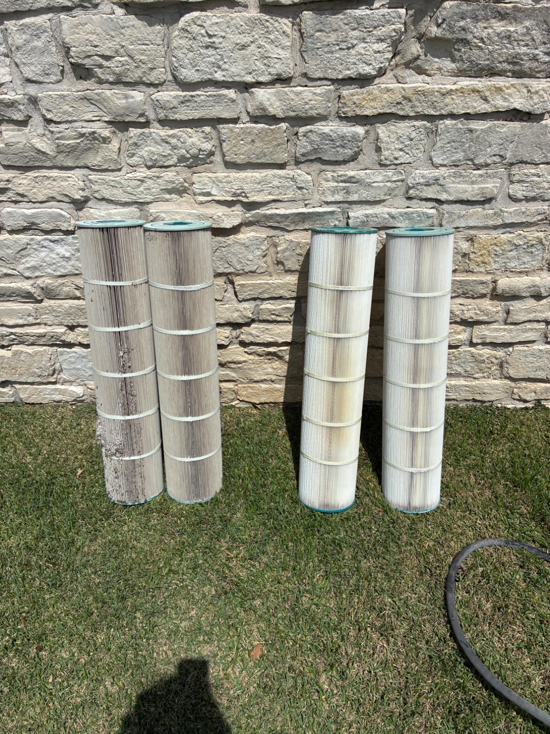 Four pool filter cartridges lined up showing dirty and clean side by side after Blue Line Pool & Spa deep-clean in Bryan-College Station