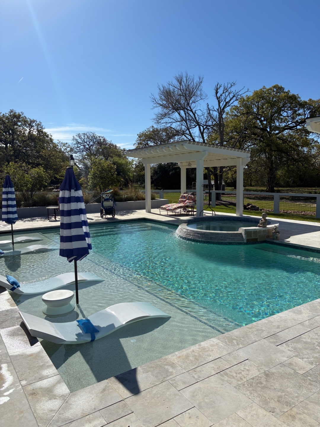 Travertine pool deck with pergola and spa serviced by Blue Line Pool & Spa in Bryan-College Station
