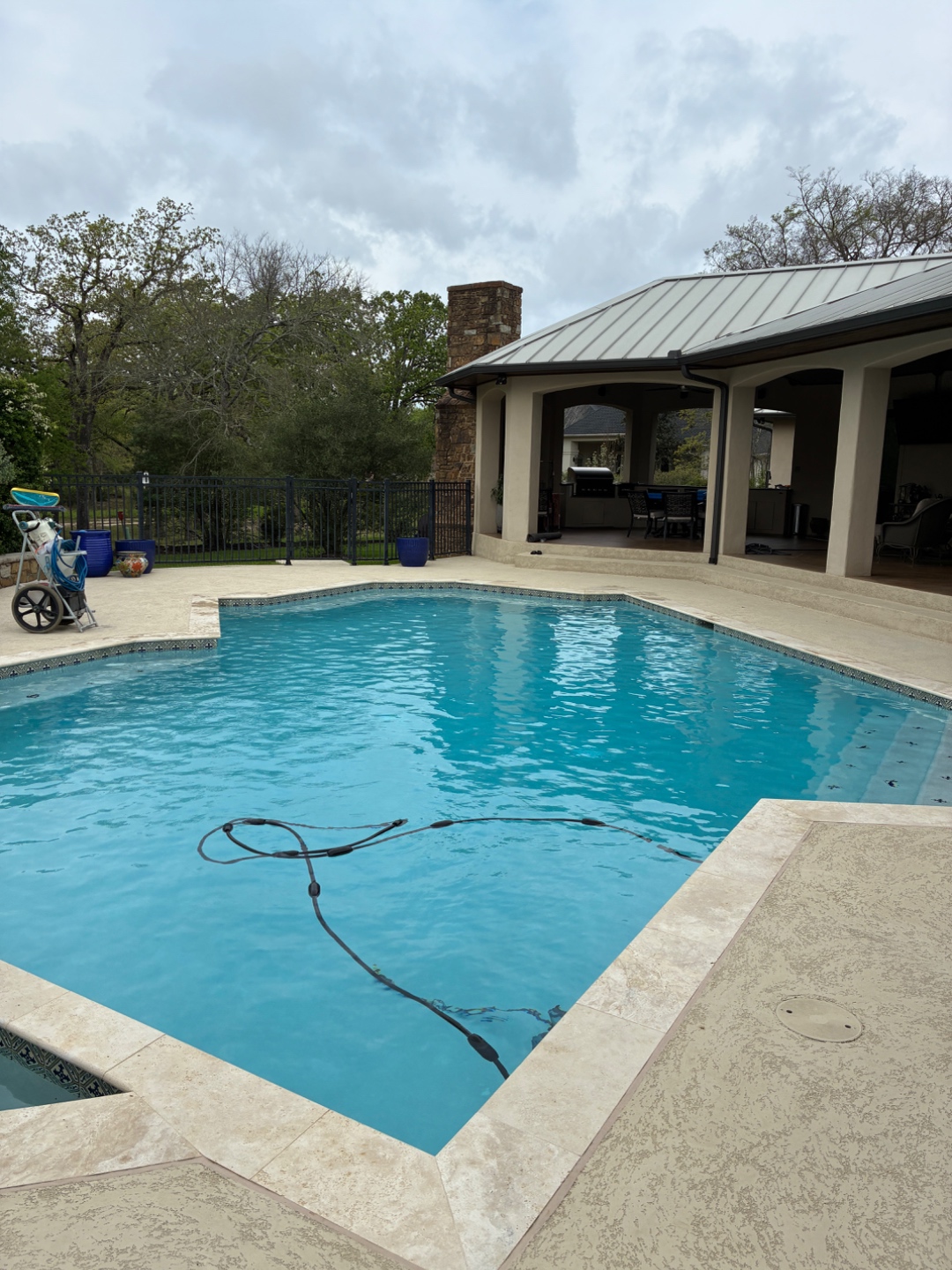 Blue Line Pool & Spa team servicing a Bryan-College Station pool with equipment cart and vacuum hose in use
